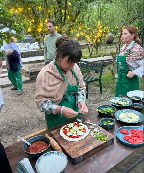 Guests topping pizzas at an outdoor table