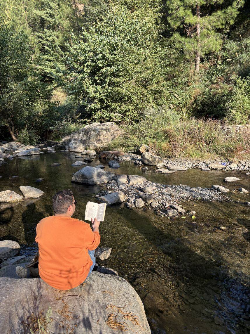 Guest reading on a boulder beside the river